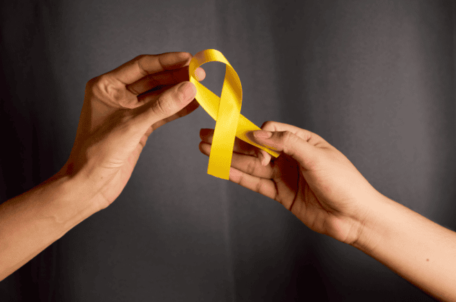sarcoma awareness month, two hands holding yellow ribbon